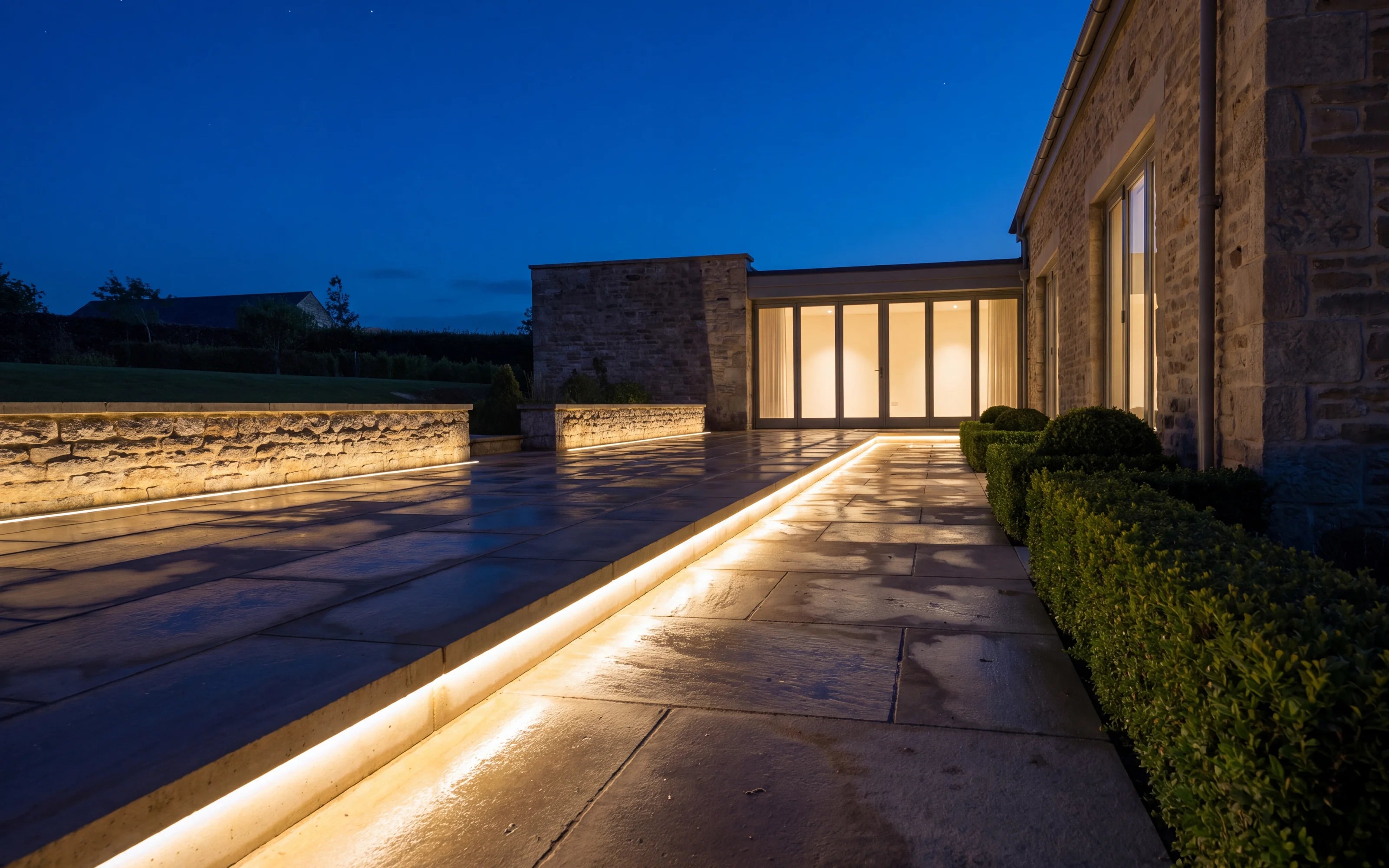 Warm white outdoor LED lighting installed along a stone terrace