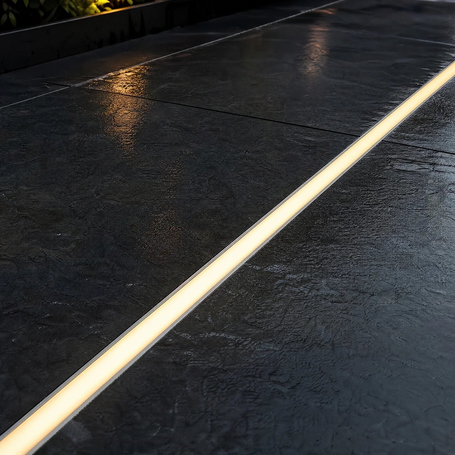 LED floor profile set flush into dark paving, lit warm white at dusk