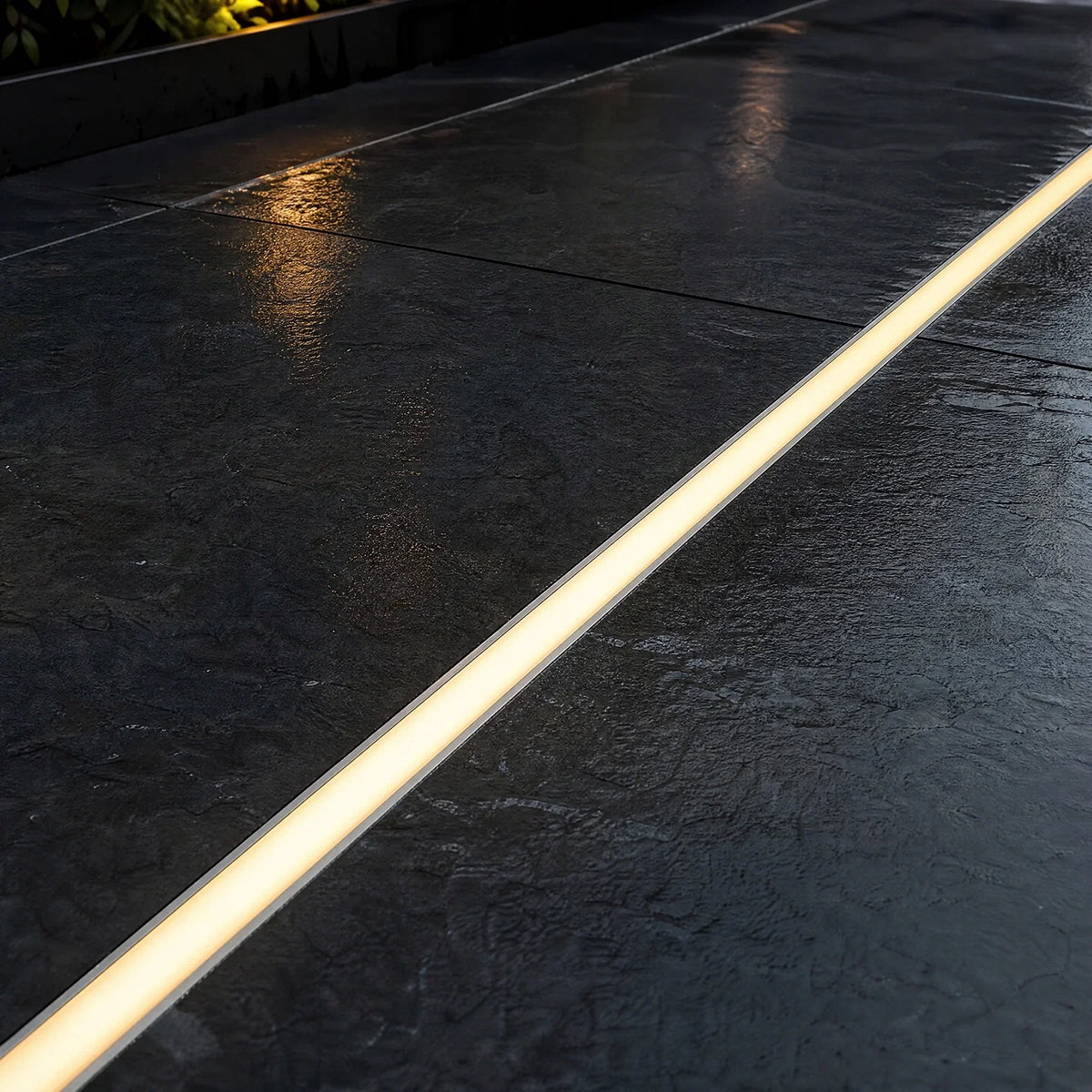 LED floor profile set flush into dark paving, lit warm white at dusk
