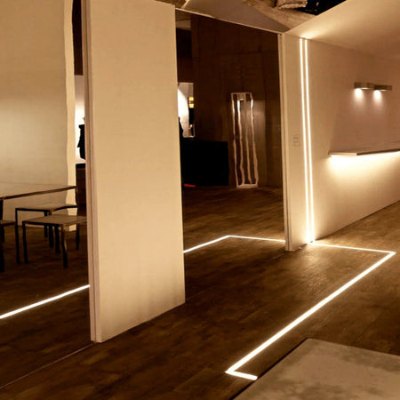 Black LED surface profile installed under a wall cabinet lighting a worktop