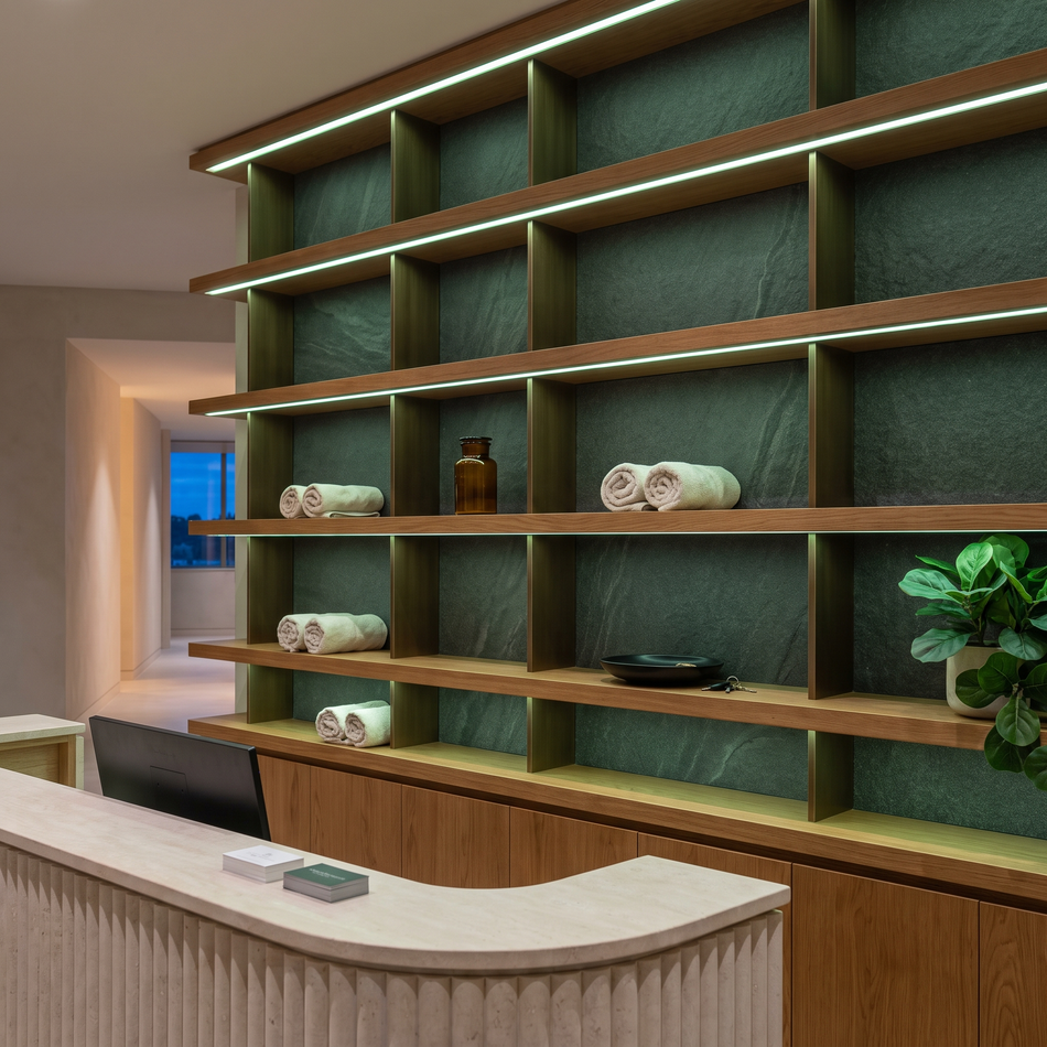 Green dot-free LED strip lighting beneath oak display shelves behind a wellness reception counter