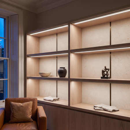 5000k white dot-free LED strip lighting beneath smoked-oak display shelving in a residential drawing room