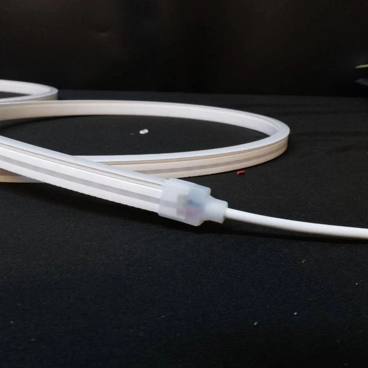 Close-up of the silicone connector and white cable on unlit neon flex