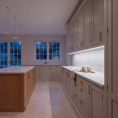 Daylight 5000K Free Cut COB LED strip lighting beneath wall cabinets in a large British kitchen in the evening; installation illustration.