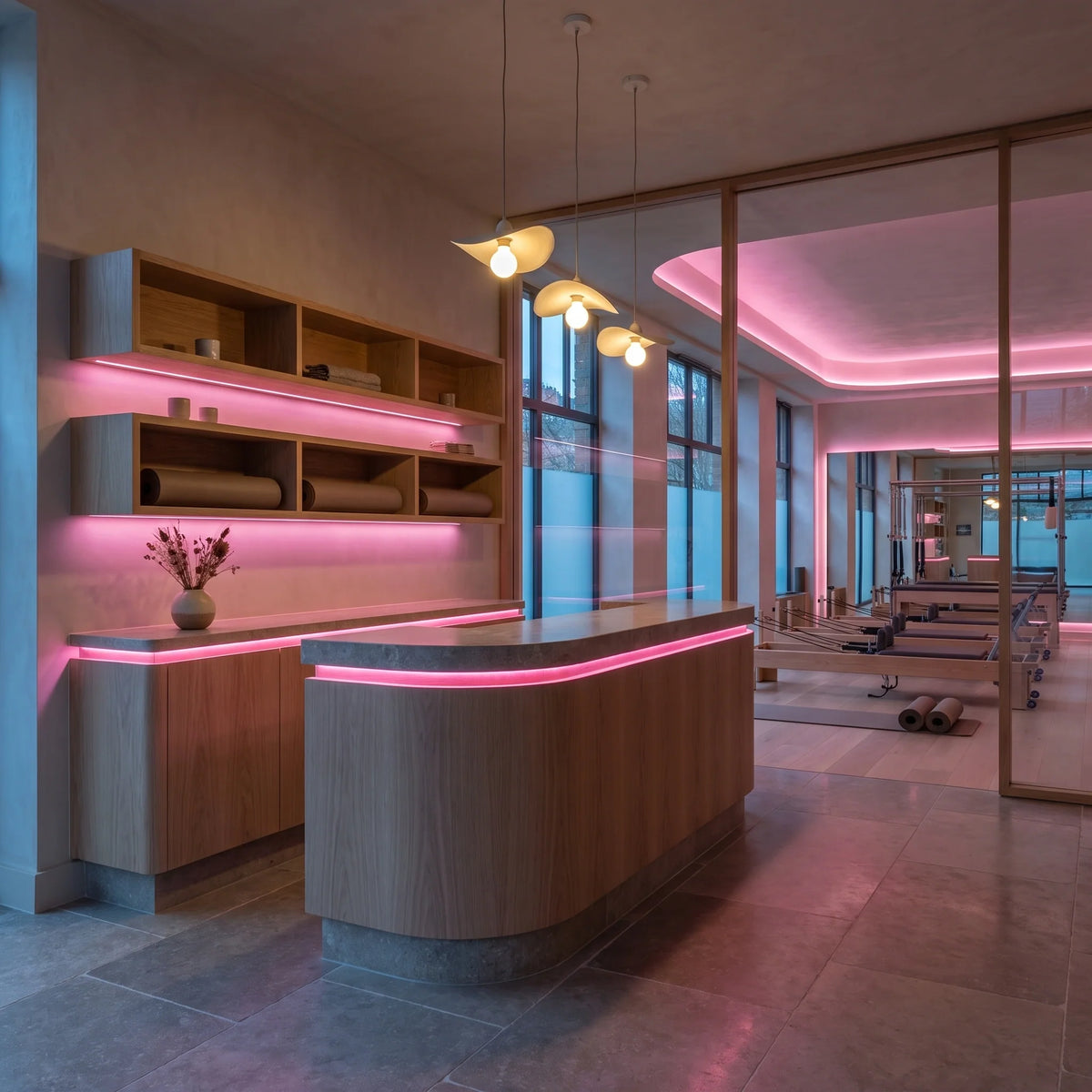 Pink 24V 10mm SCOB LED strip installed beneath a Pilates studio reception desk and in ceiling coving; installation visual.