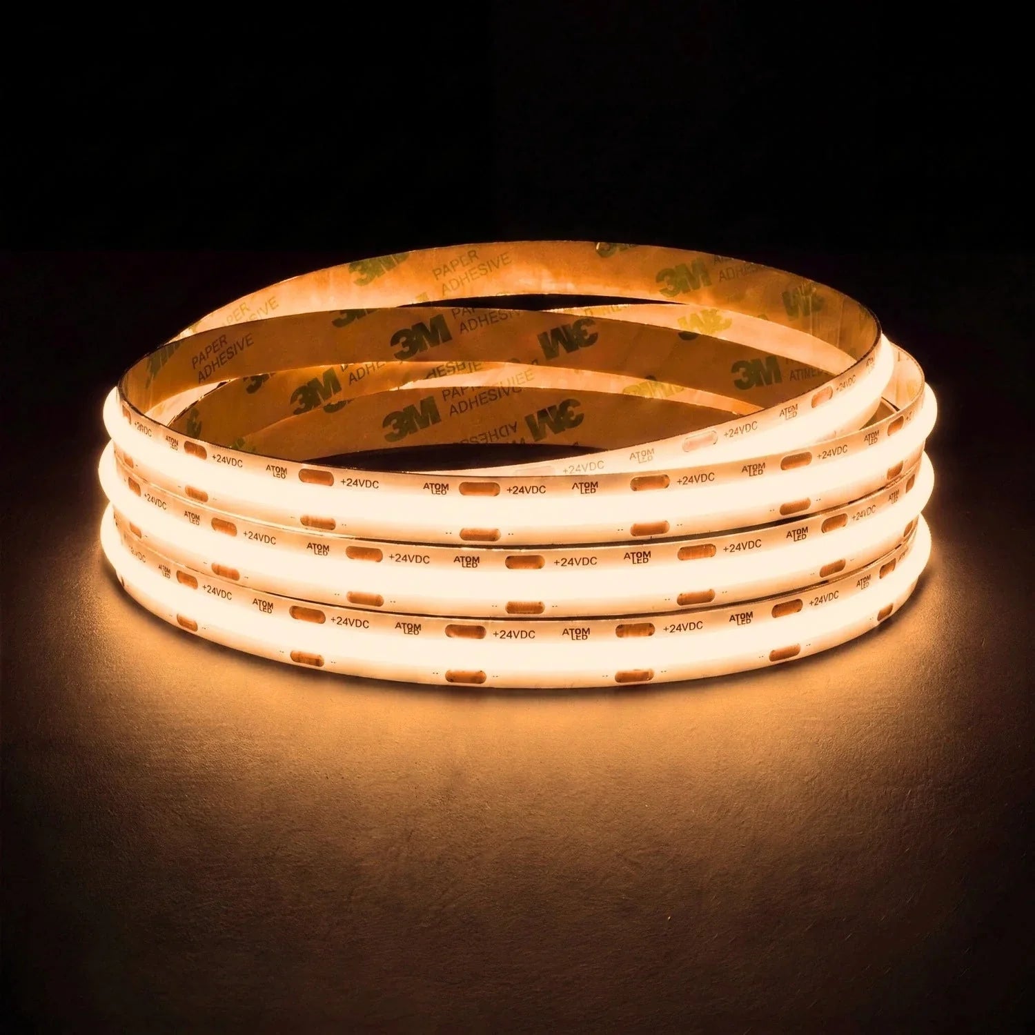 Warm White 2700K SCOB LED strip coil illuminated on a dark background, 24V DC and 10mm wide.