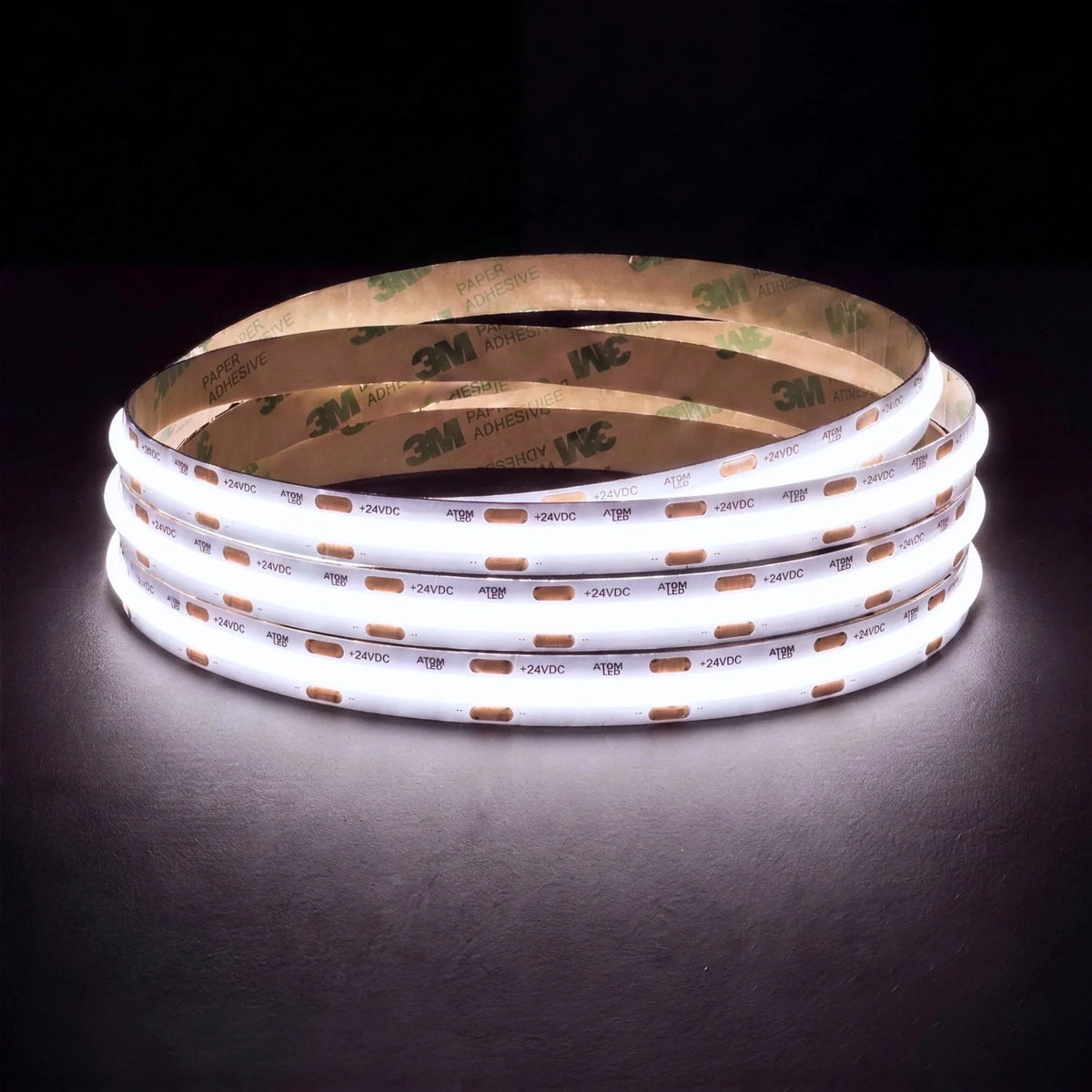 Daylight white 5000K SCOB LED strip coil illuminated on a dark background, 24V DC and 10mm wide, with copper connection pads