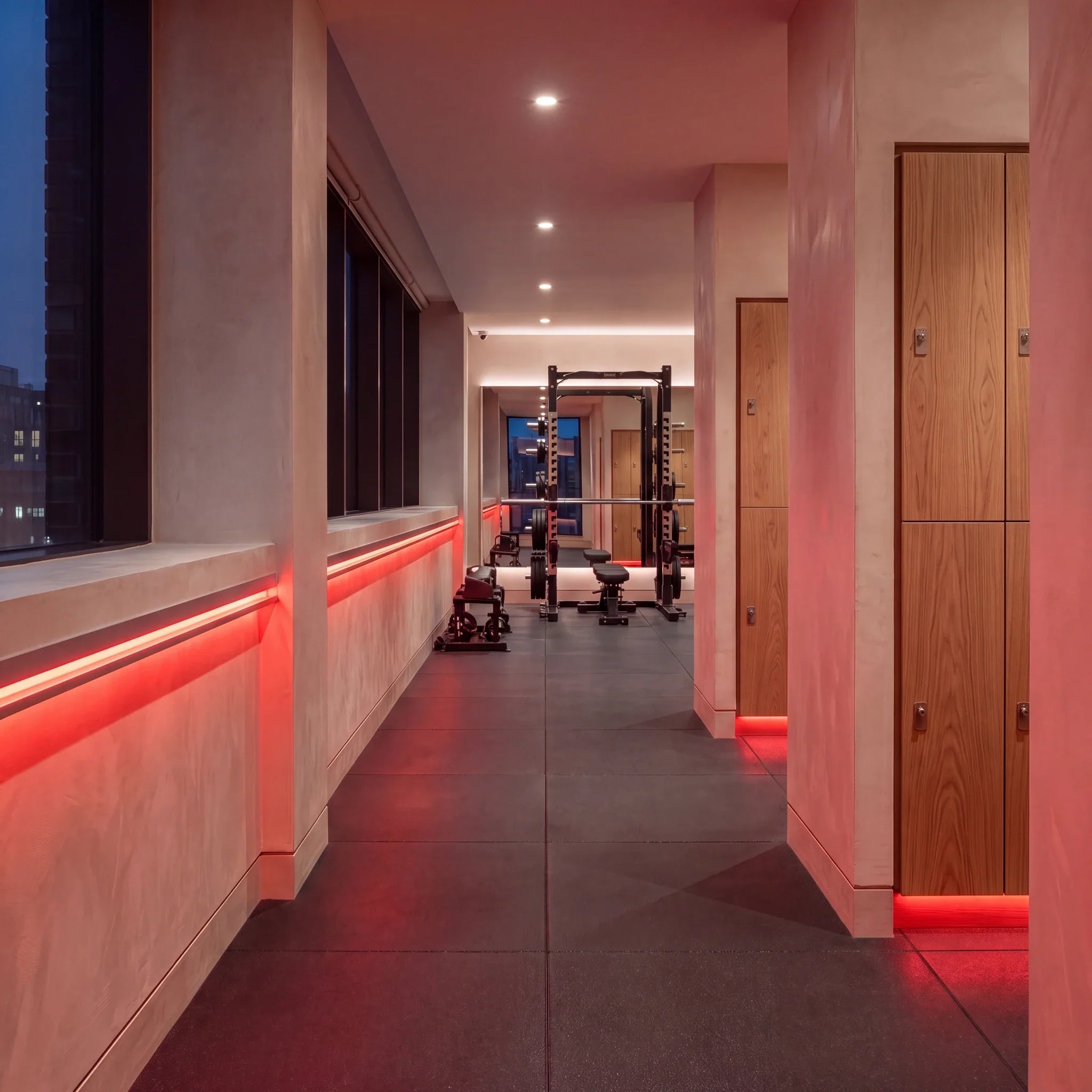 Red SCOB LED strip lighting along a fitness corridor beside oak lockers and a strength-training area; installation illustration.