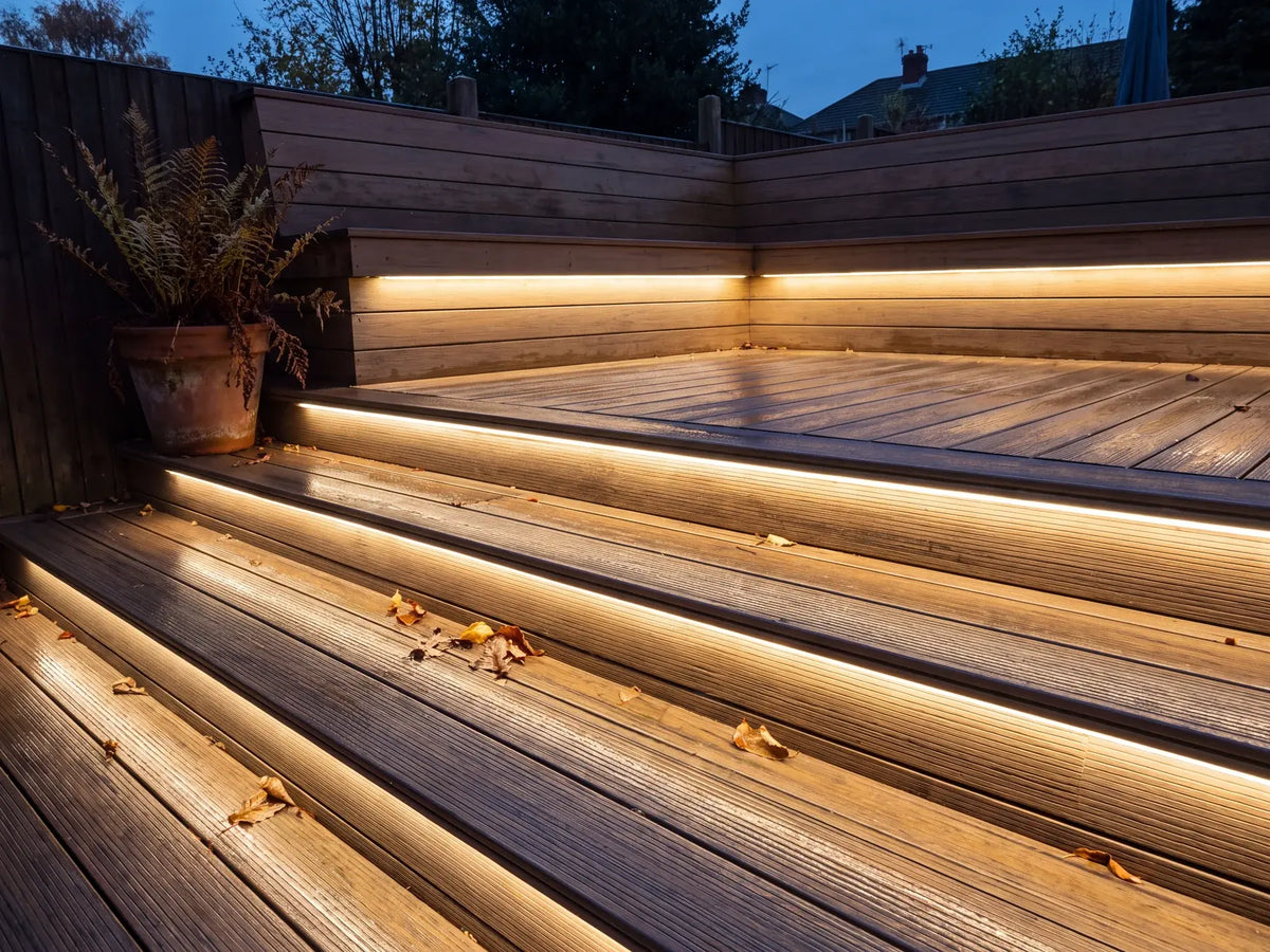 Warm white LED neon flex recessed into garden decking, lit at dusk with damp boards