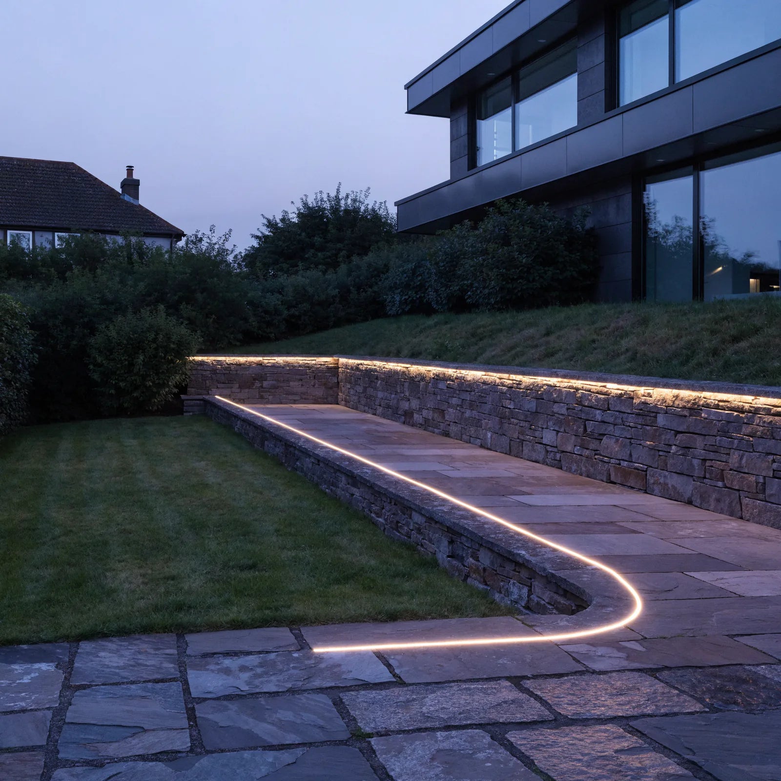 Extra-long continuous warm white LED lighting installed around a stone garden terrace