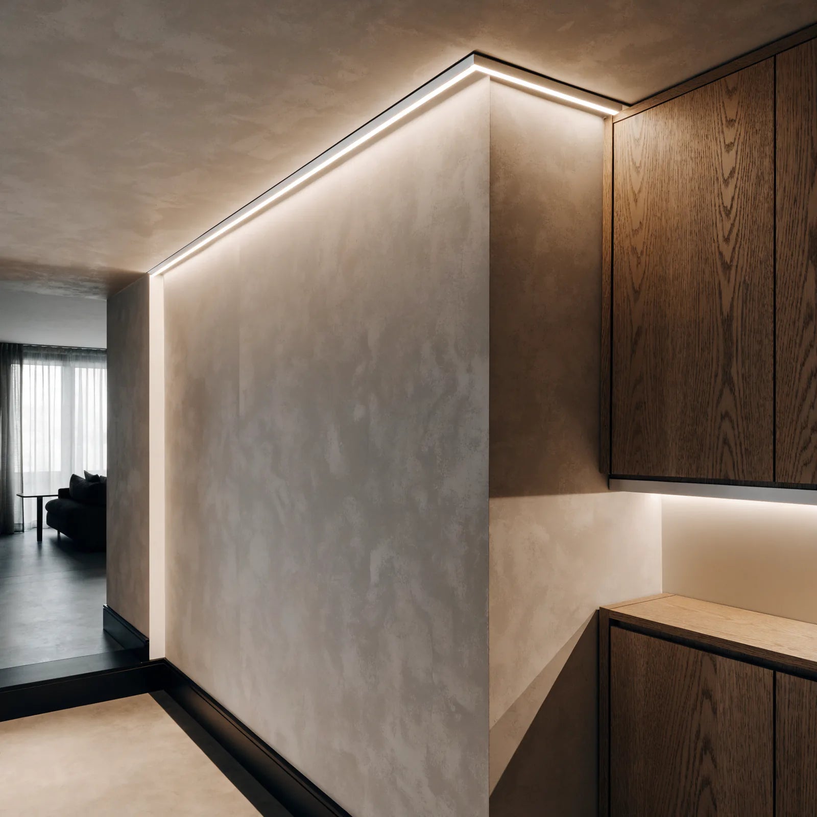 Recessed aluminium LED profiles installed along a ceiling and built-in oak joinery