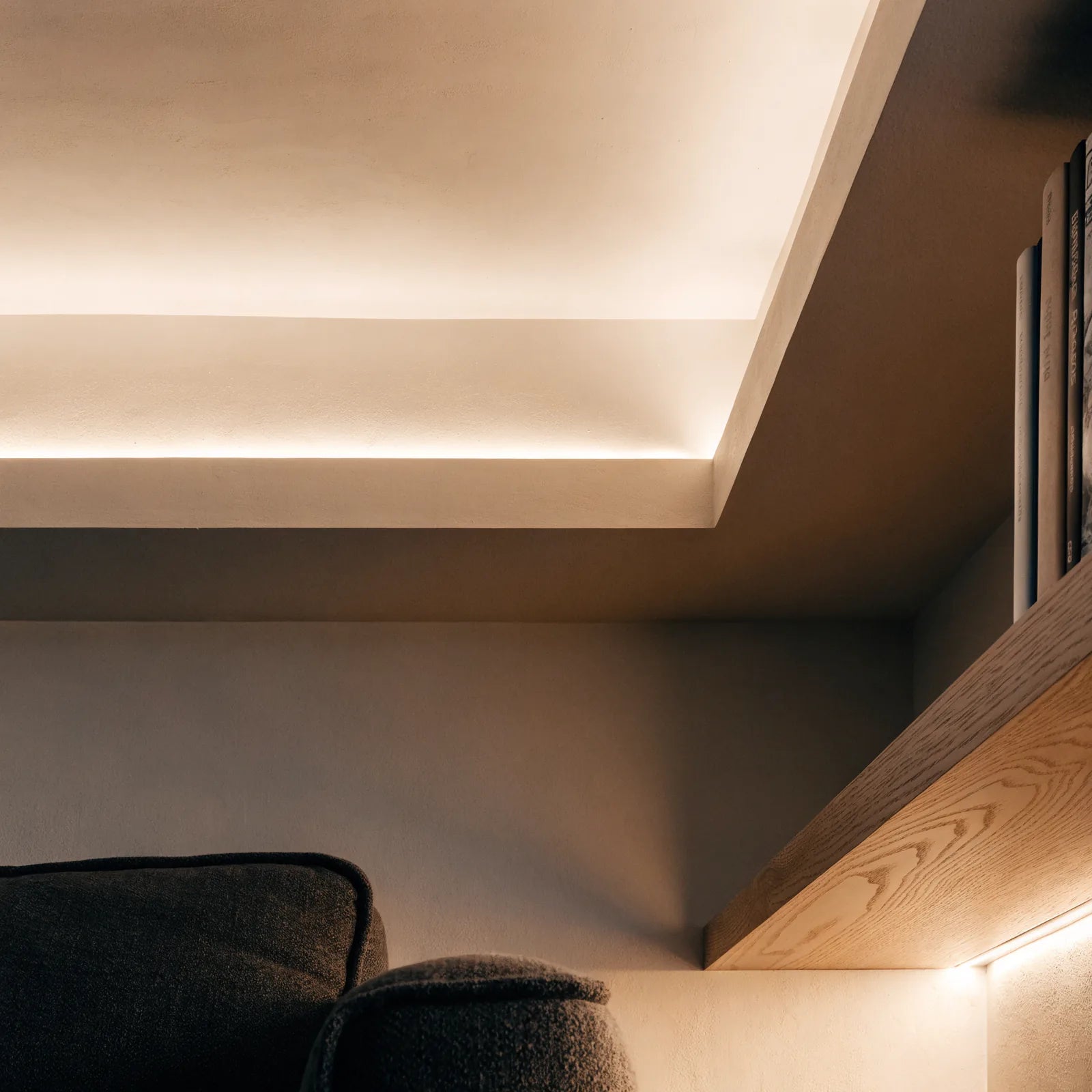 Warm white LED strip lighting concealed in ceiling coving and beneath oak shelving